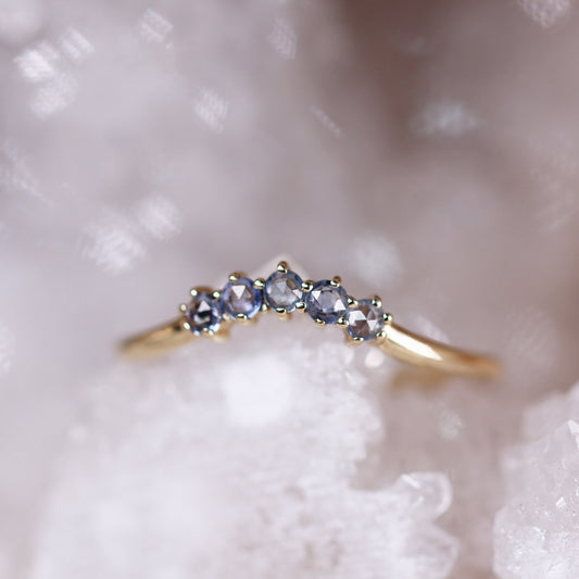Gold contour band featuring five blue rose-cut sapphires in a shared prong setting with a gentle curve design.