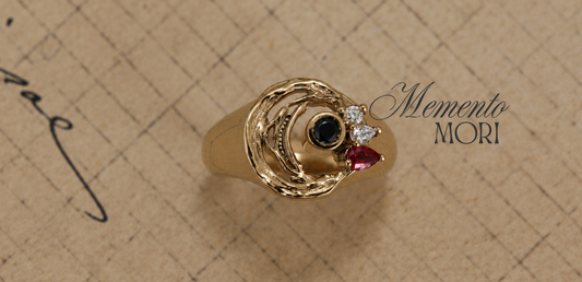 Le Conte’s 14K gold brushstroke ring with a red sapphire and black and white diamonds on handwritten paper, beside the words “Memento Mori.”