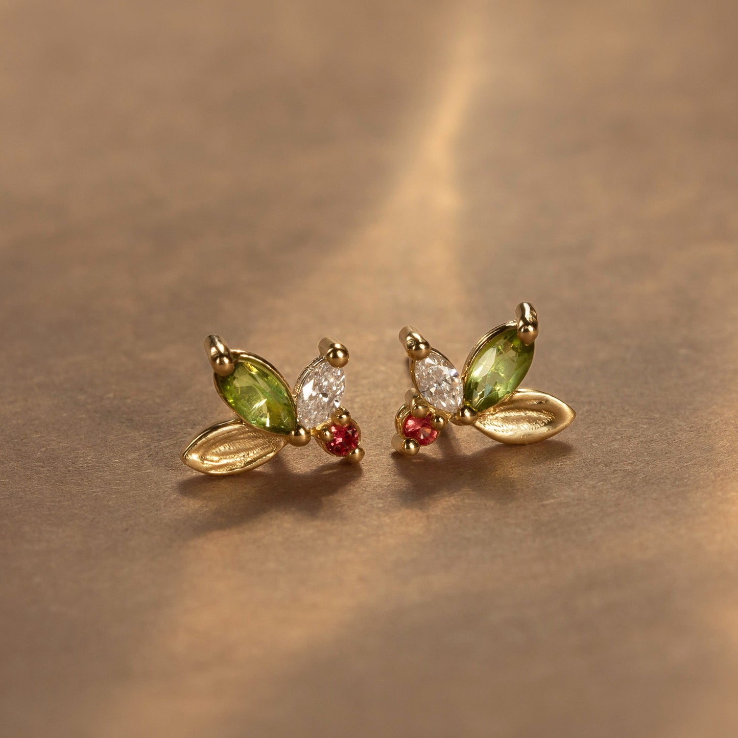 This holiday edition of our original Monet's Lily Petals Earrings is adorned with a brushstroke-textured gold leaf, an apple-green tourmaline, and a brilliant-cut white diamond. At its heart, a scarlet-red sapphire emulates the vibrant berry of the mistletoe. A delicate yet striking statement piece, perfect for the season!

mini canvas, artist's canvas, paintings, painter, tourmaline, sapphire, earrings, studs, dainty jewelry, brushstroke texture